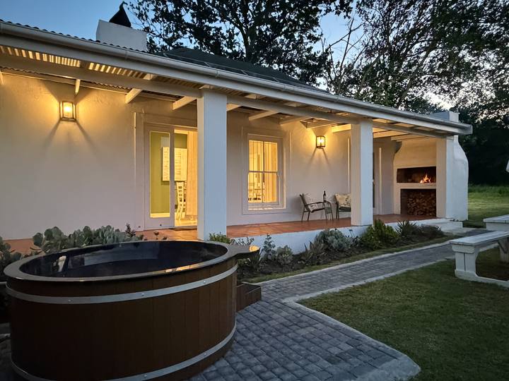 The cottage glowing at dusk with its hot tub
