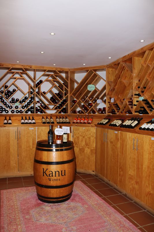 Wine shop corner with timber racks and a Kanu barrel on a rug