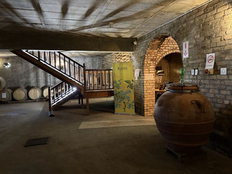The cellar with its wooden staircase, barrels and a large clay amphora