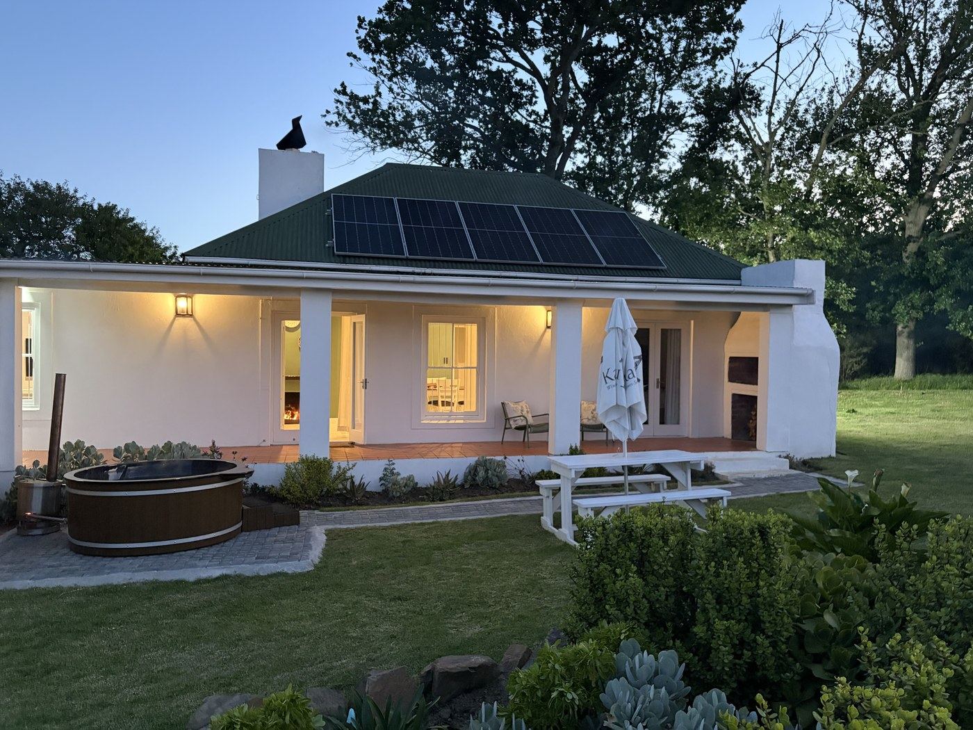 The Kanu vineyard cottage at dusk, with its wooden hot tub and covered patio